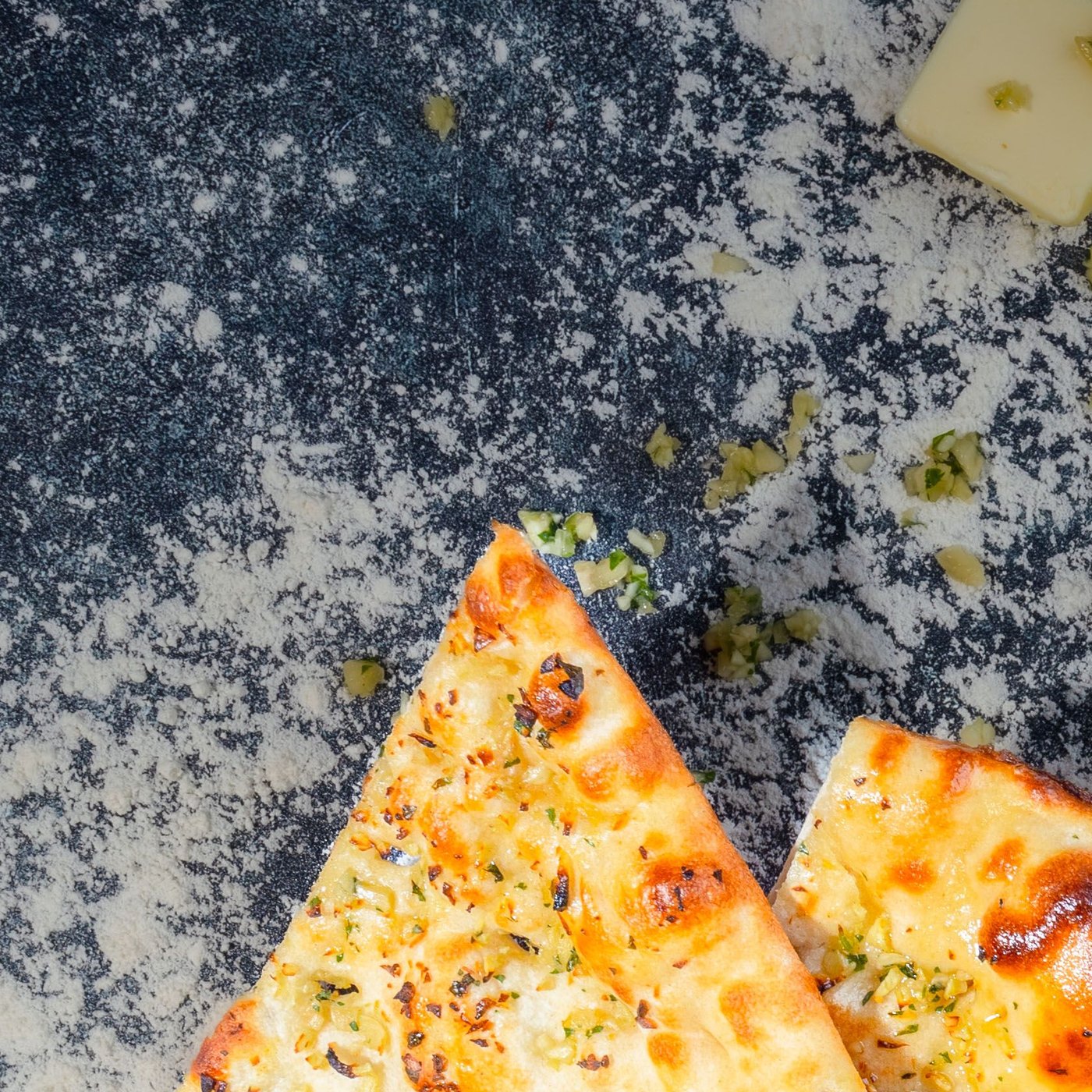 Garlic naan with charred spots, herbs and cubes of butter.