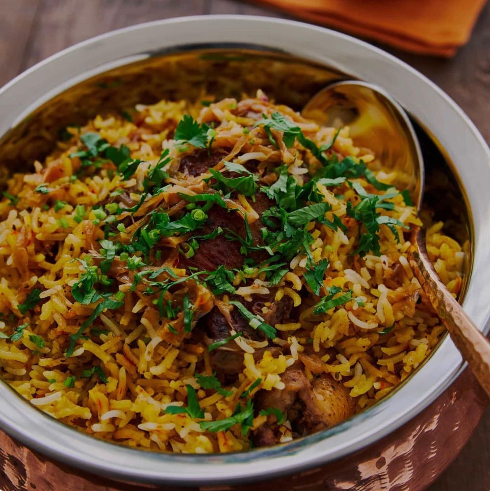 Fragrant biryani served in a copper handi with cilantro.