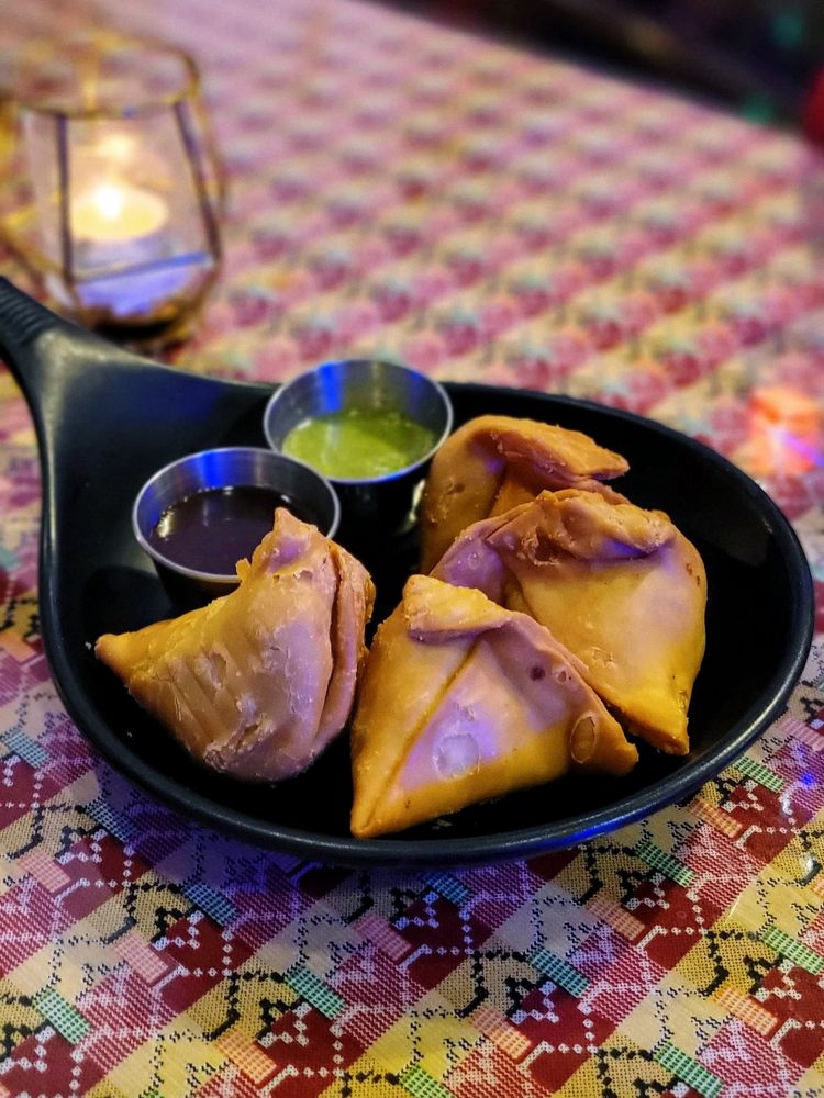 Four golden fried samosas with mint and tamarind chutney.