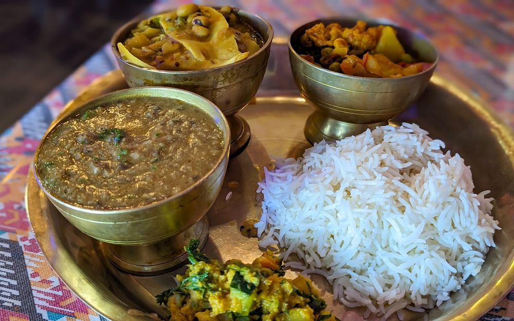 Brass thali with rice, dal and vegetable curries.