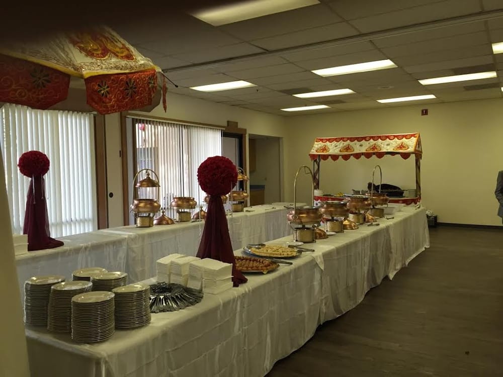 Chafing dishes and plates of food arranged on a catering table.